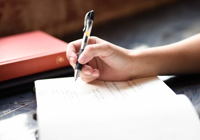 hannah-olinger-8eSrC43qdro-unsplash Independent author writing on a notepad